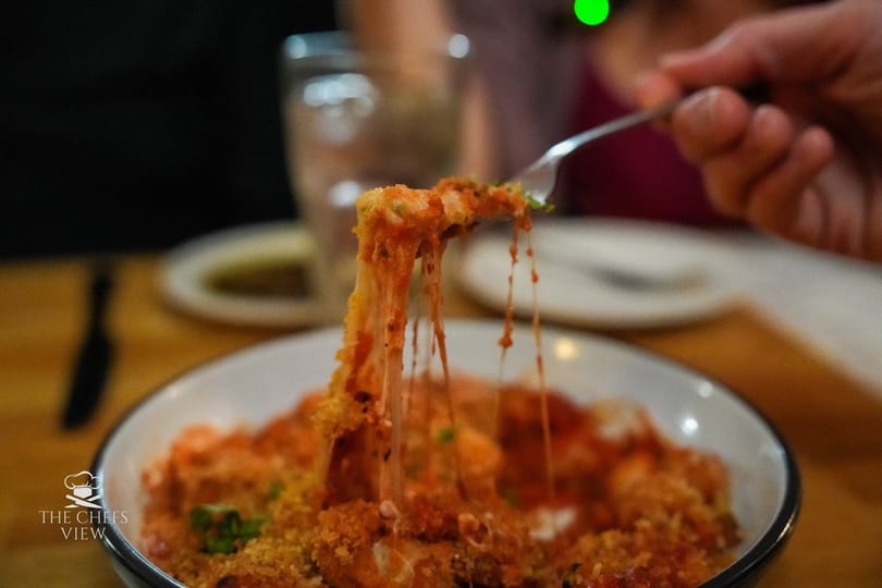 A fork lifts cheesy, saucy pasta from a bowl, creating long, delicious cheese pulls.